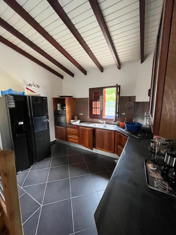 una cucina con armadi in legno e frigorifero nero di NOTRE MAISON a Sainte-Anne