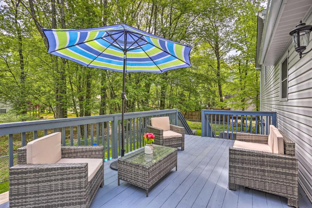 a patio with chairs and a table with an umbrella at Poconos Family Getaway with Fire Pit and 2 Game Rooms in Pocono Summit