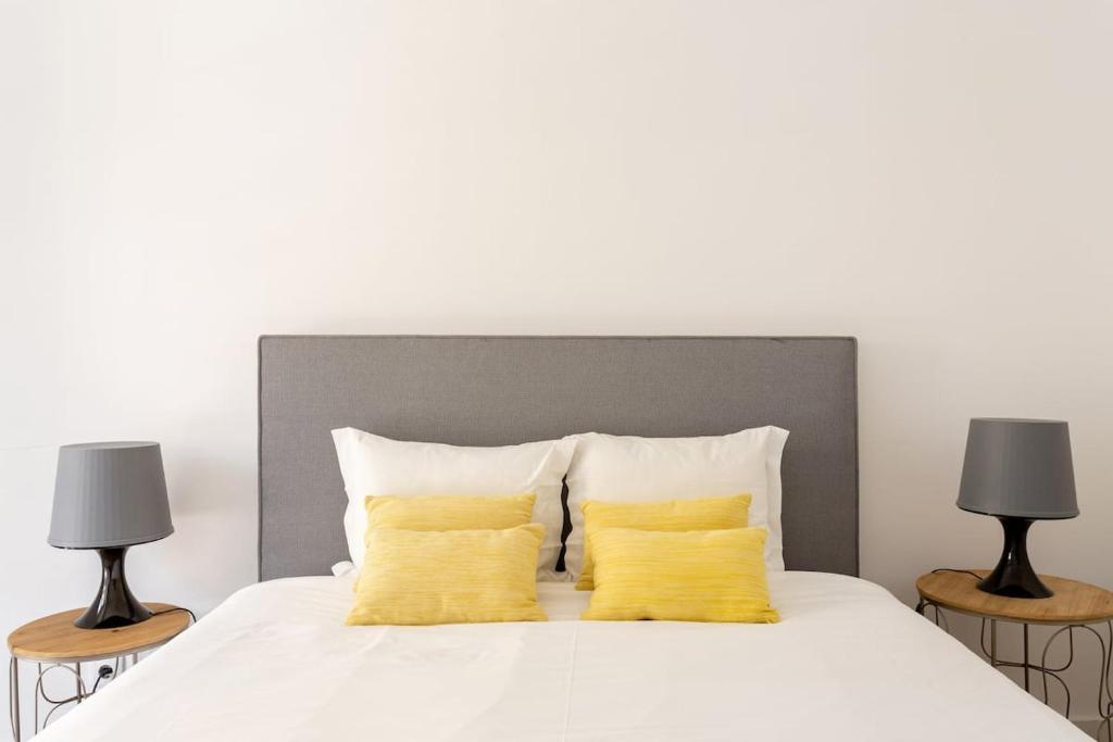 リスボンにあるCentral Bairro Altoの白いベッド(黄色い枕2つ、ランプ2つ付)