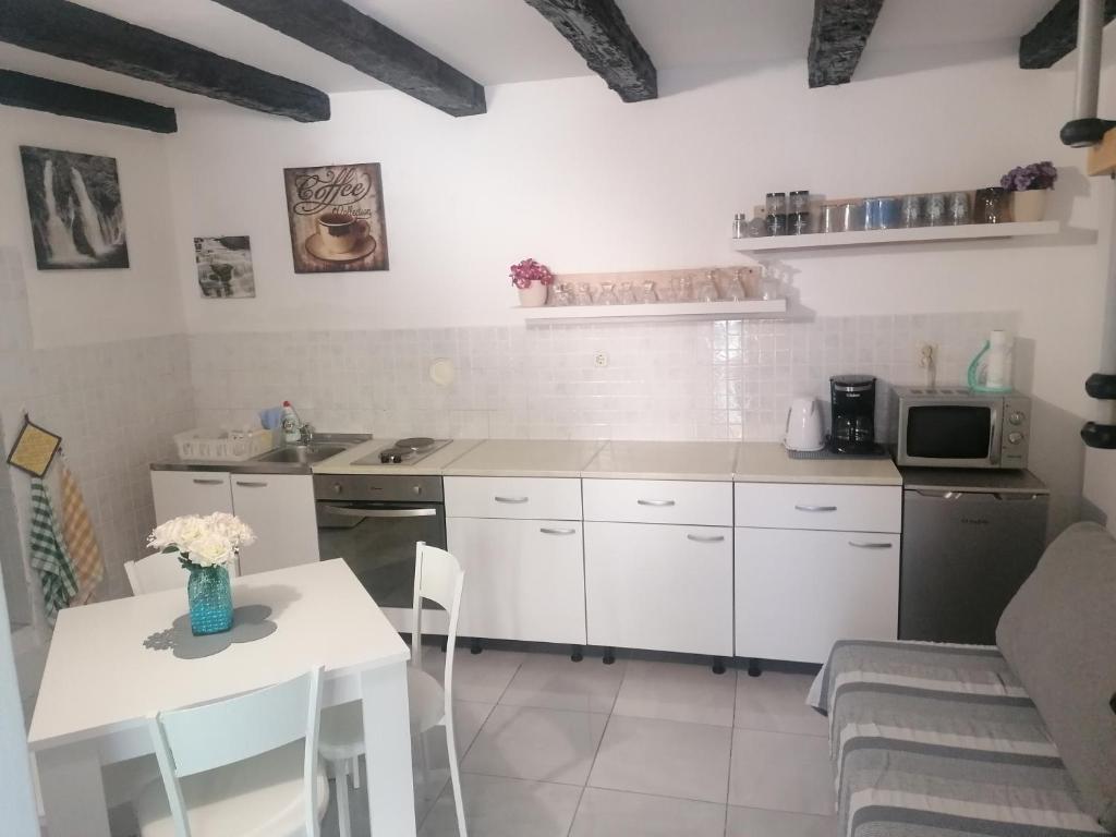 een keuken met witte kasten, een tafel en een magnetron bij Apartments with a parking space Povile, Novi Vinodolski - 16127 in Povile