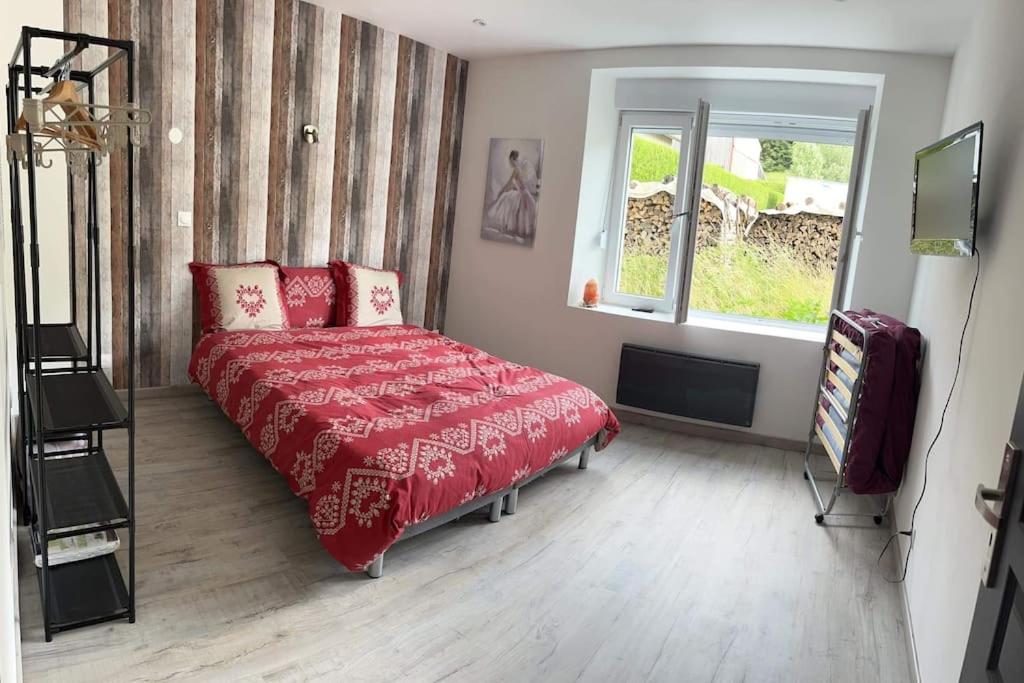 a bedroom with a red bed and a window at Cocon lumineux près des pistes in La Bresse