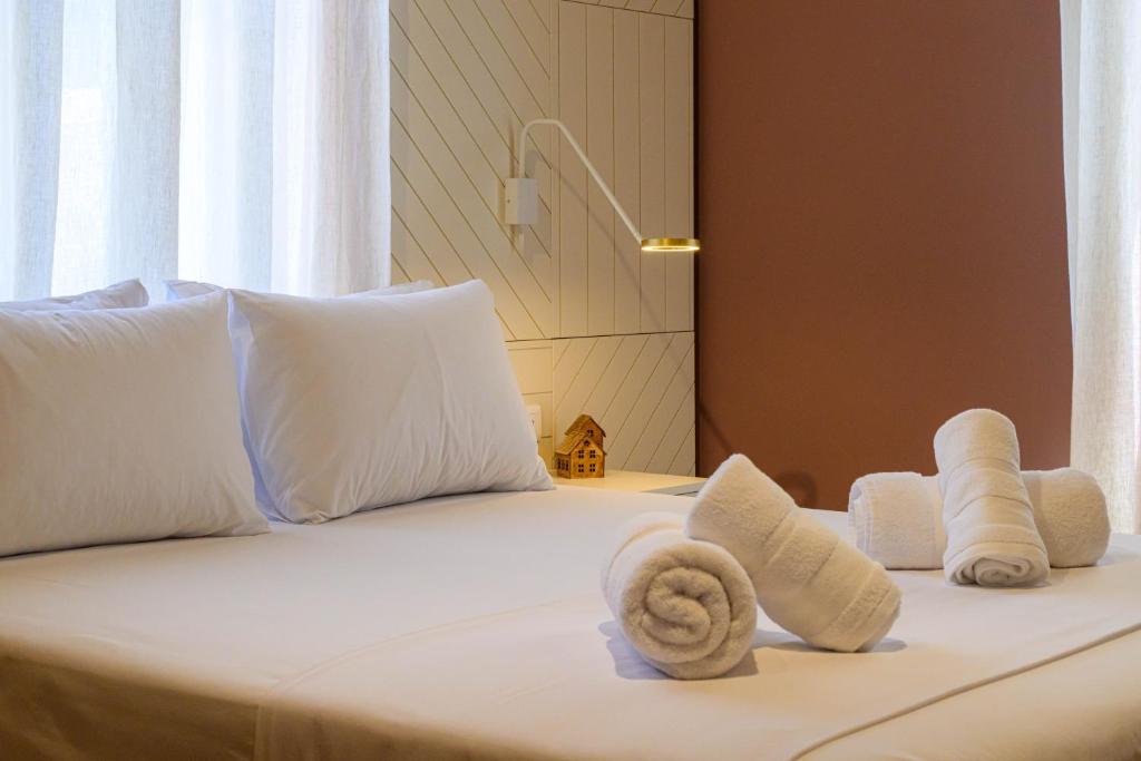 a white bed with towels on it with a window at BlueBlood - The Rooms in Kalamata
