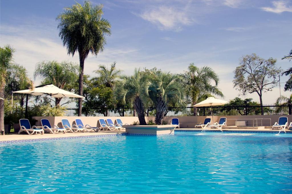 uma piscina com cadeiras e guarda-sóis num resort em Turismo Hotel Casino em Corrientes