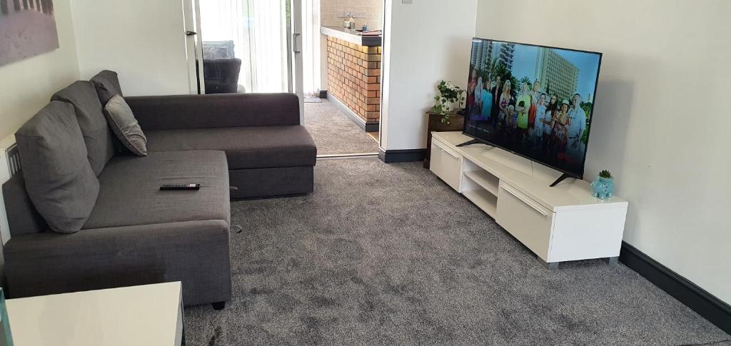 a living room with a couch and a flat screen tv at Green Haven Villa - 4BR Spacious House with Hot tub, Ample Parking, Air Condition, WIFI, Netflix, Patio & Garden in Kidlington