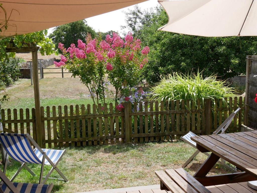 une clôture en bois avec une table, des chaises et des fleurs roses dans l'établissement Gîte de caractère au cœur des vignes avec jardin, vélos et équipements bébé - FR-1-306-796, à Châteauthébaud