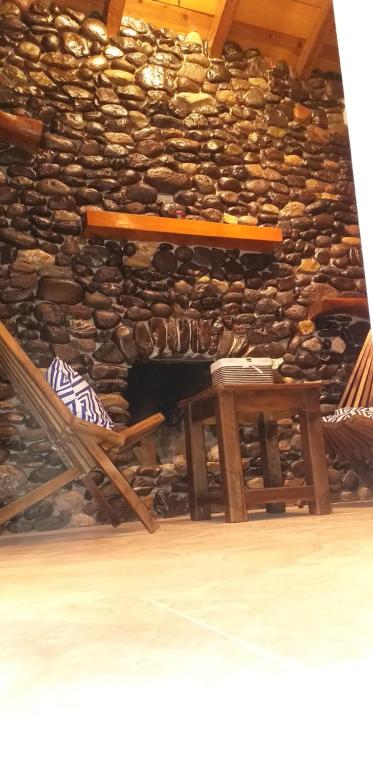 una silla y una mesa frente a una pared de piedra en Cabaña Los Ángeles, en Huasca de Ocampo