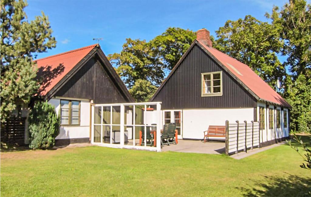 una pequeña casa en blanco y negro con un patio en Beautiful Home In Aakirkeby With Kitchen, en Spidsegård