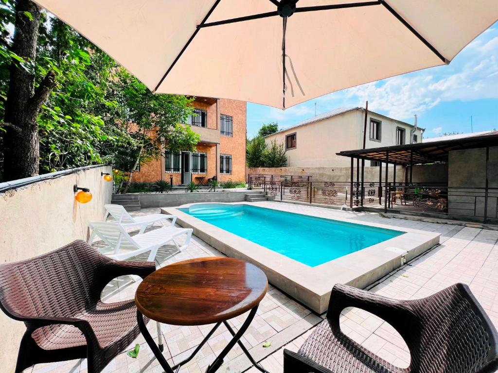 a pool with chairs and a table and an umbrella at Awesome Large 3 Floor Villa Dilijan , 8 Bedrooms+4.5 Bathrooms+Swimming Pool, Nice Mountain View in Dilijan