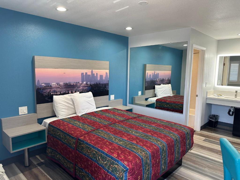 Habitación de hotel con cama y espejo en Sahara Inn - Los Angeles en Los Ángeles