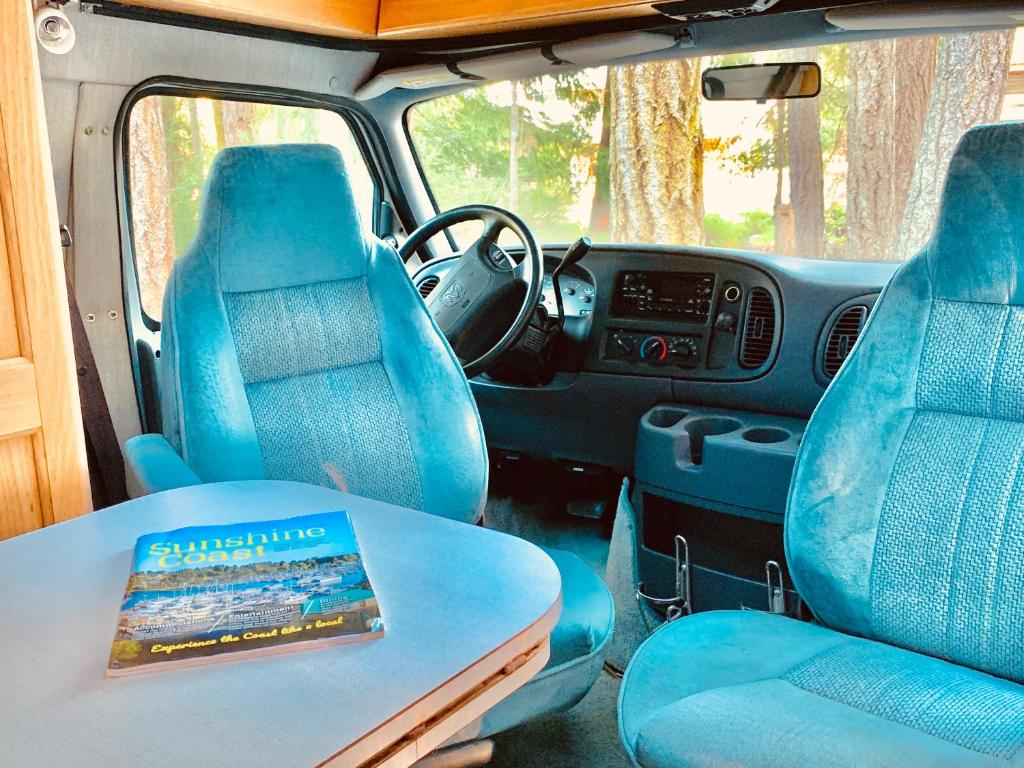 a van with blue seats and a book on a table at Shady Van in the Woods in Gillies Bay