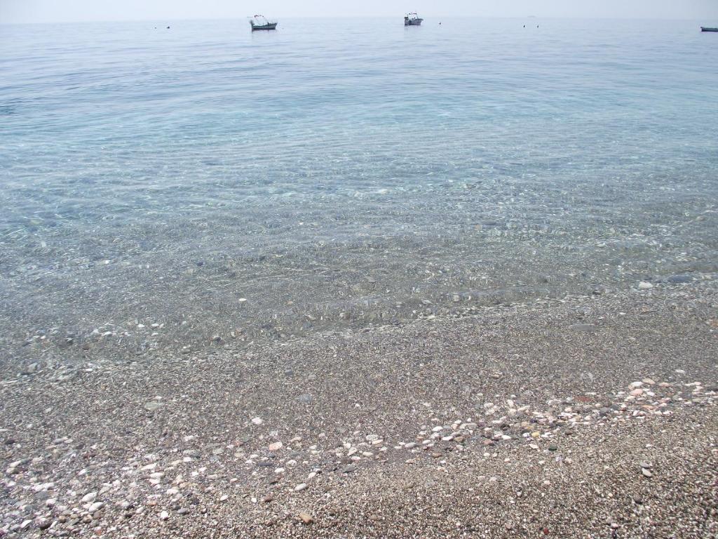 a sandy beach with two boats in the water at B&B Il Mare degli Dei in Letojanni