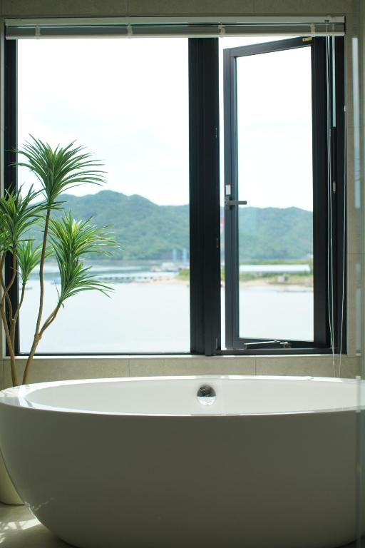 a bath tub in front of a window with a plant at Villacation the Loose in Minamiawaji