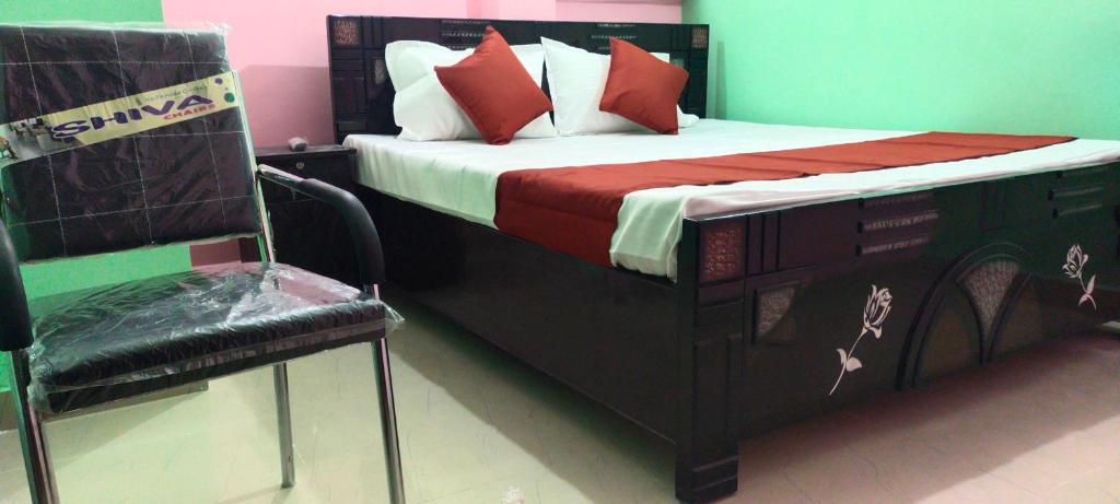 uma cama com almofadas vermelhas e uma cadeira num quarto em SPOT ON Hotel Royal Garden em Dānāpur