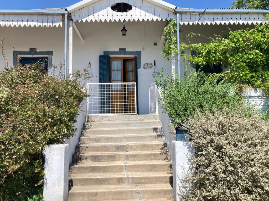 una escalera que conduce a una casa blanca con una puerta azul en Alojarte en Punilla- Casona Azul hasta 12 personas en Huerta Grande