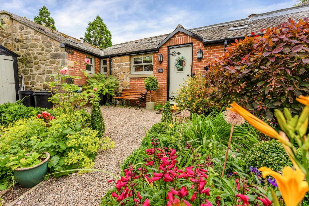 a garden in front of a brick house with flowers at Nurse's Cottage in Alnwick