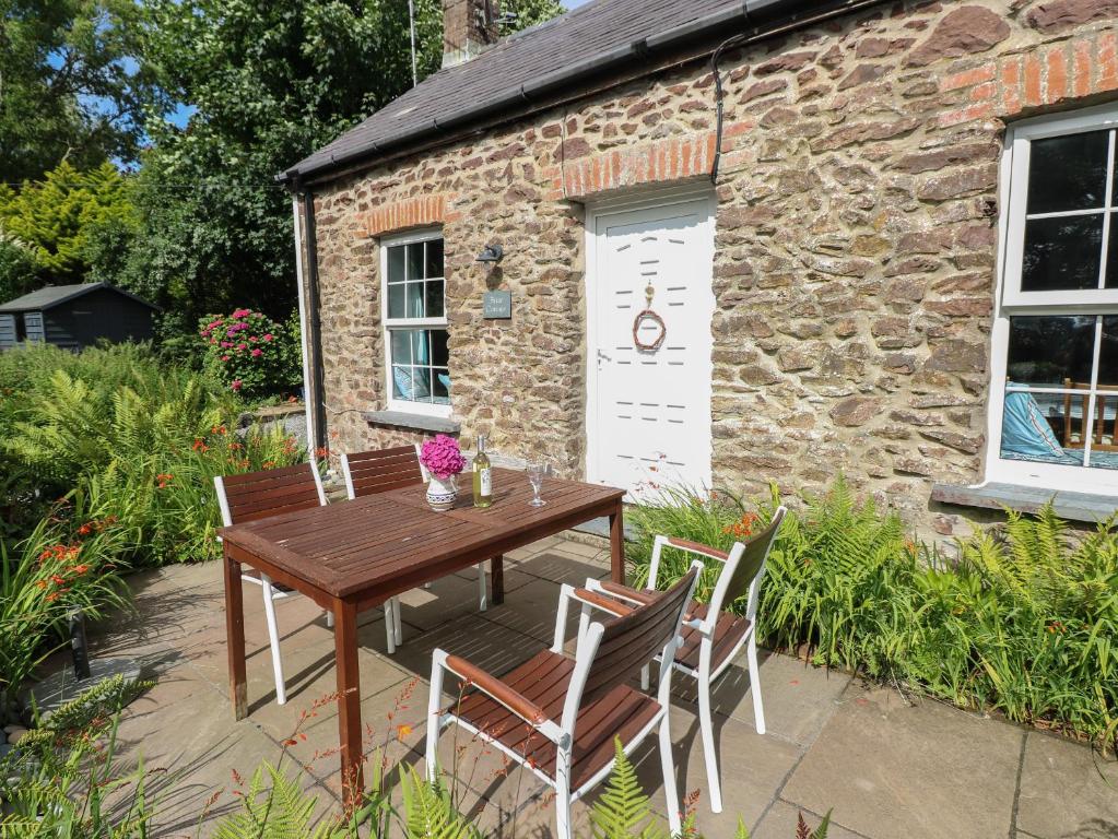 a wooden table and chairs in front of a building at Briar Cottage in Neyland
