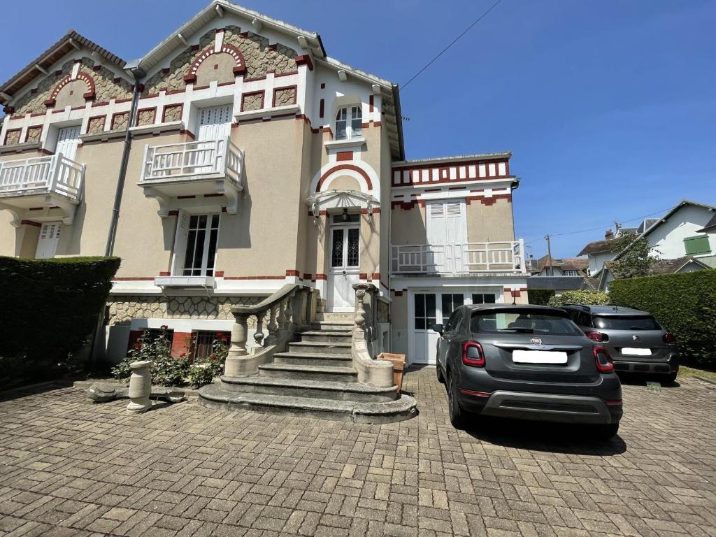 une voiture garée devant un grand bâtiment dans l'établissement Villa spacieuse à Cabourg, 200m plage, jardin, 5 chambres, parking, ménage inclus - FR-1-487-359, à Cabourg