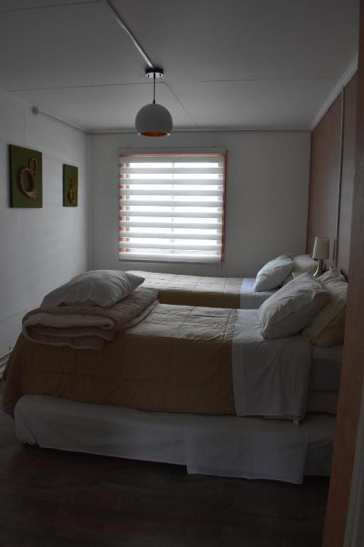 um quarto com uma cama grande e uma janela em Casa Entre Ulmos y Lengas em Puerto Natales