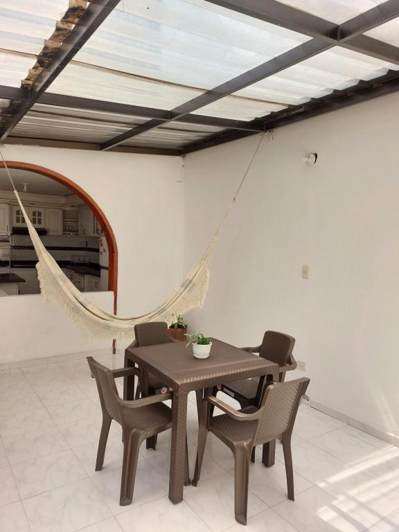 a dining room with a table and chairs and a hammock at Casa Estación Modelia, near to the airport. in Bogotá