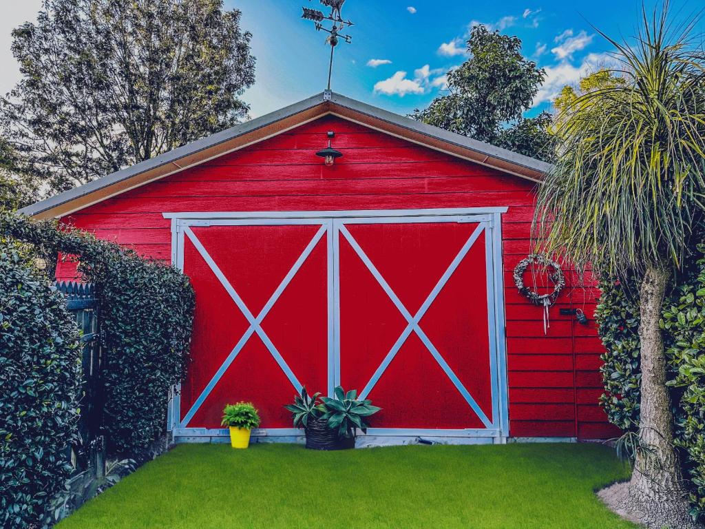 um celeiro vermelho com uma porta branca num quintal em The Red Barn: right in the heart of historic Berry em Berry