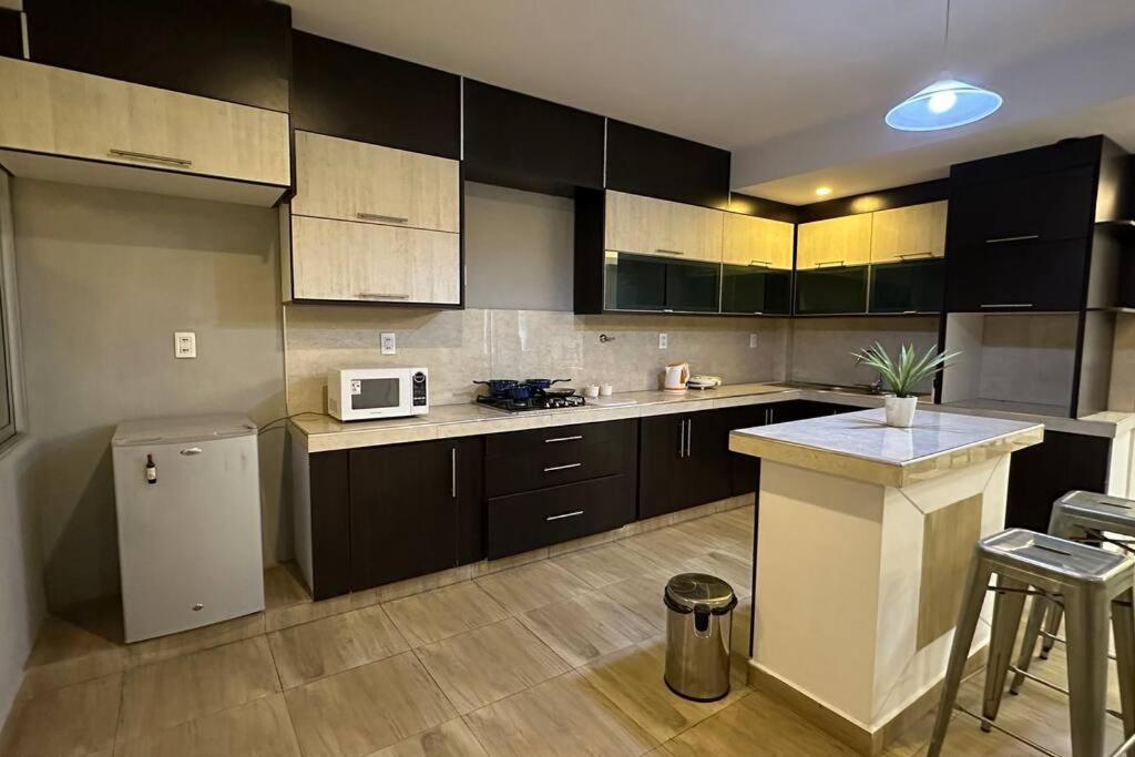 a kitchen with black cabinets and a white microwave at Hermoso y amplio departamento in Tarija