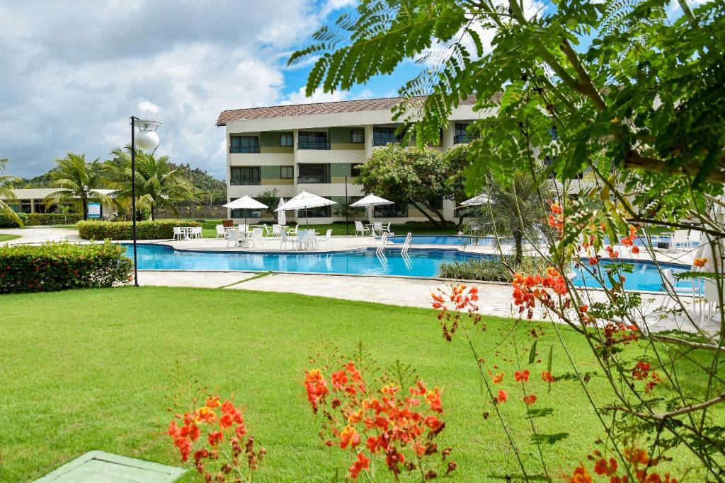 a resort with a swimming pool and a building at Carneiros Beach Resort - Flats Cond à Beira Mar in Praia dos Carneiros