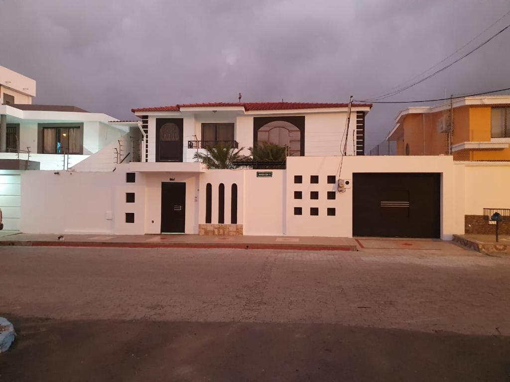 una casa blanca con dos puertas de garaje en una calle en Confort, en Manta