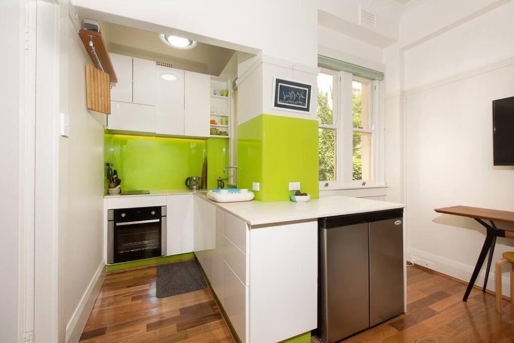 uma cozinha com armários verdes e brancos e uma mesa em Tranquil 1 Bedroom Apartment - Rushcutters Bay Self-Catering em Sydney