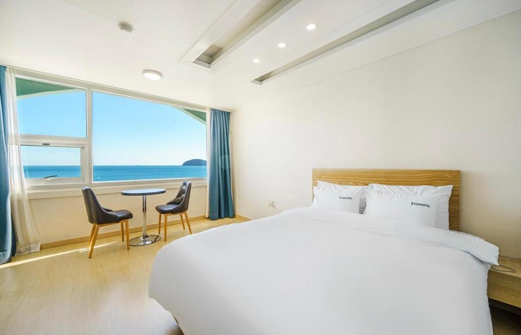 um quarto com uma cama grande e uma mesa com cadeiras em VIEW Hotel Geoje em Geoje