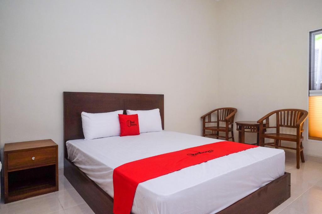 a bedroom with a bed with a red blanket on it at RedDoorz Syariah near Transmart Pabelan Solo in Kartosuro