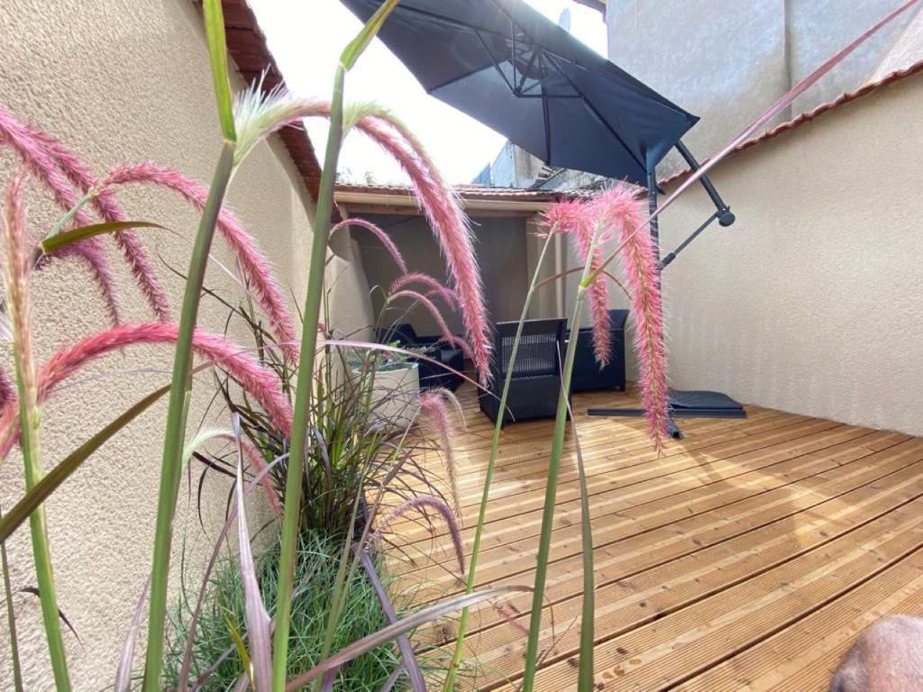 um pátio com um guarda-chuva e algumas plantas em La Perle du Gier - Maison-Climatisée-Terrasse em Rive-de-Gier