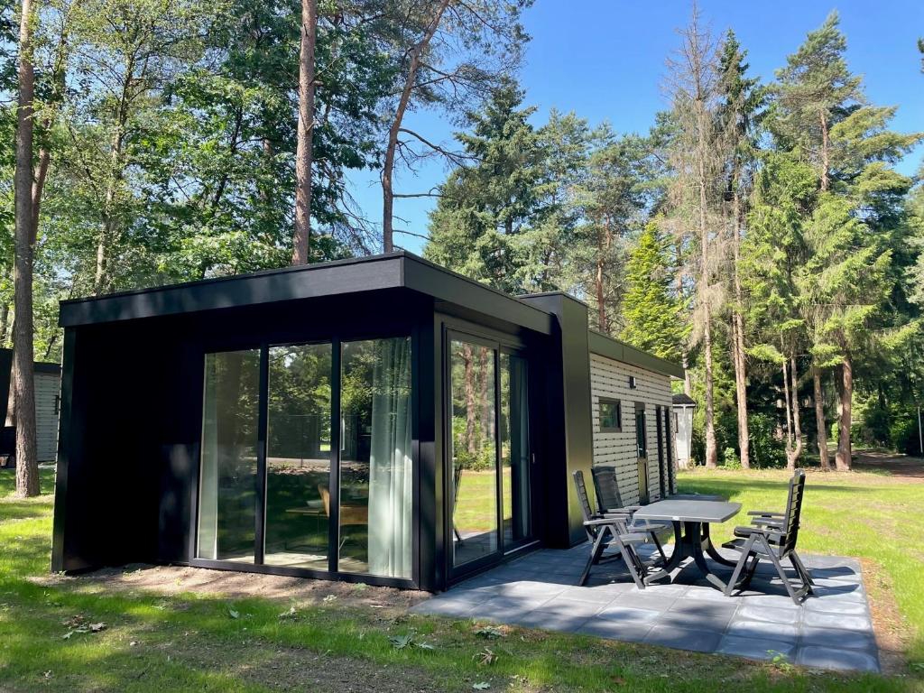 uma pequena casa preta com uma mesa e cadeiras em Vakantiepark Hertenhorst em Beekbergen