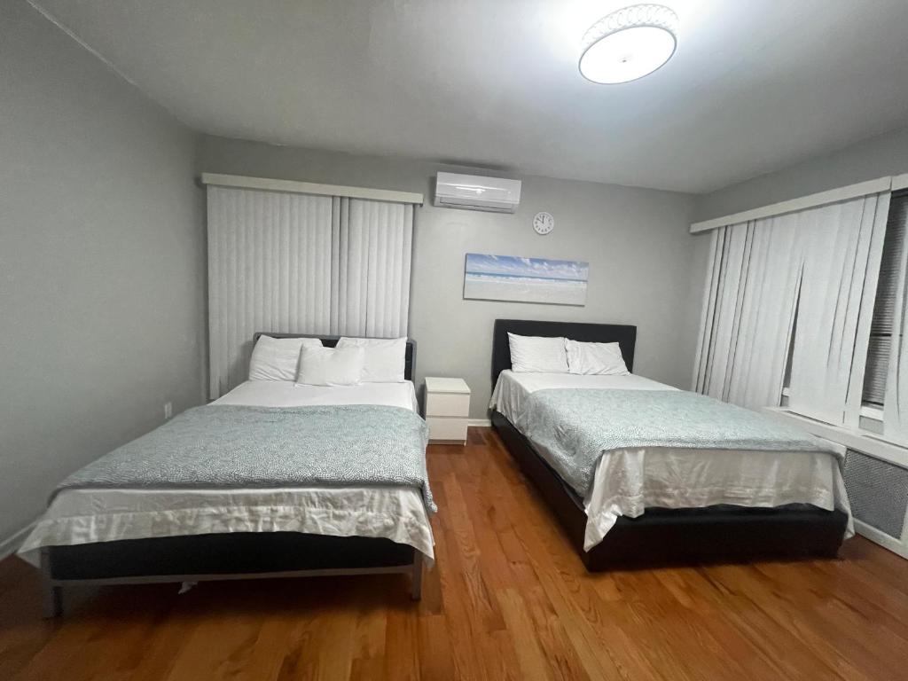 2 łóżka w pokoju z drewnianymi podłogami i oknami w obiekcie Large 1 Bedroom Apartment in the heart of the Bronx w mieście Unionport