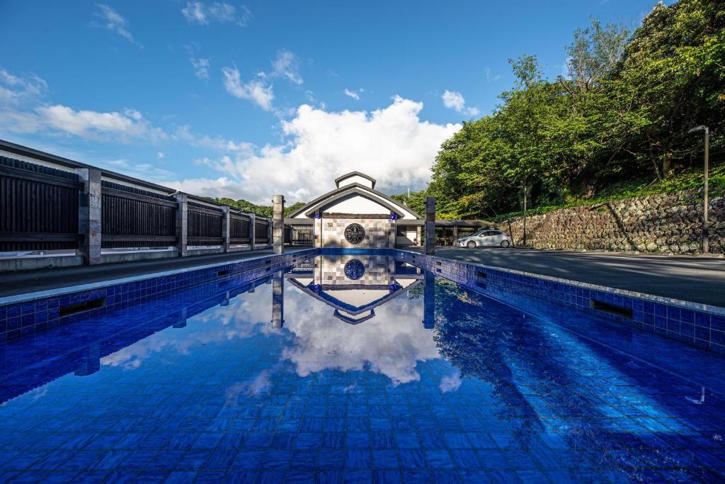 a swimming pool with a house and its reflection in the water at Fugaku Gunjo in Izu