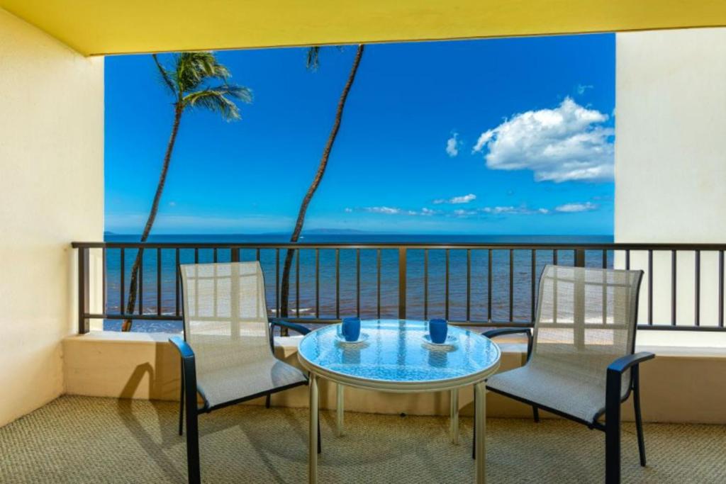 a balcony with a table and chairs and a view of the ocean at SUGAR BEACH RESORT, #326 condo in Kihei