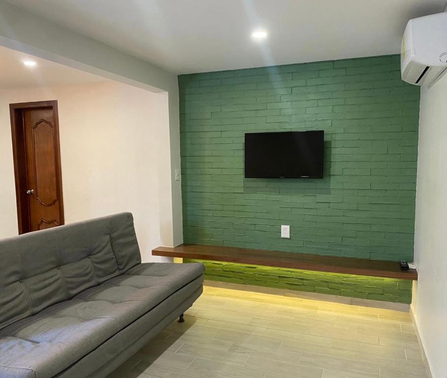 sala de estar con sofá y pared verde en Casa Lily en Orizaba