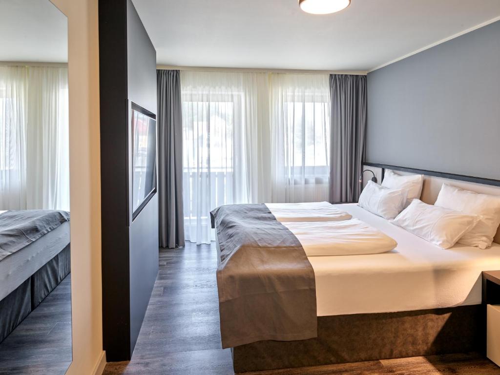Hotel Innsento - Health Campus Passau في باساو: غرفة فندقية بسرير كبير ونوافذ