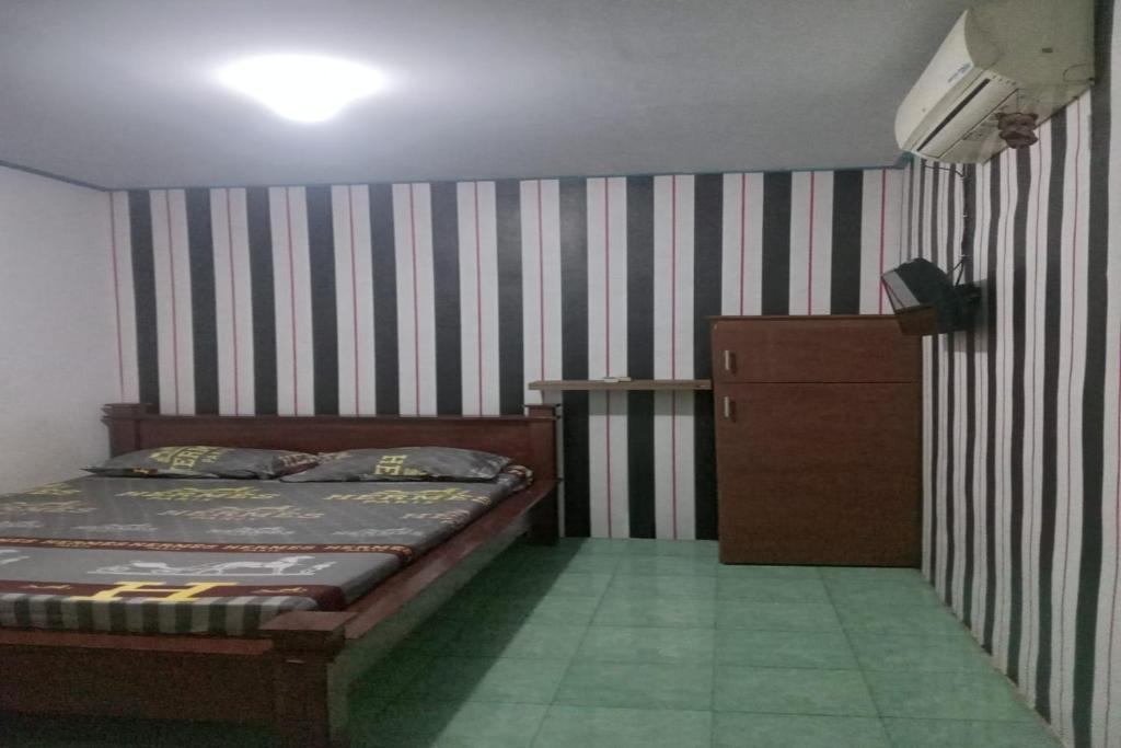 a bedroom with a bed and a dresser in it at OYO 92816 Ana Homestay in Banyuwangi