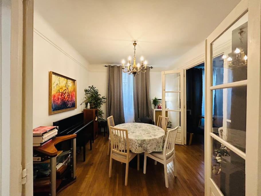 une salle à manger avec une table, des chaises et un lustre dans l'établissement Beautiful and spacious apartment in Paris, à Paris