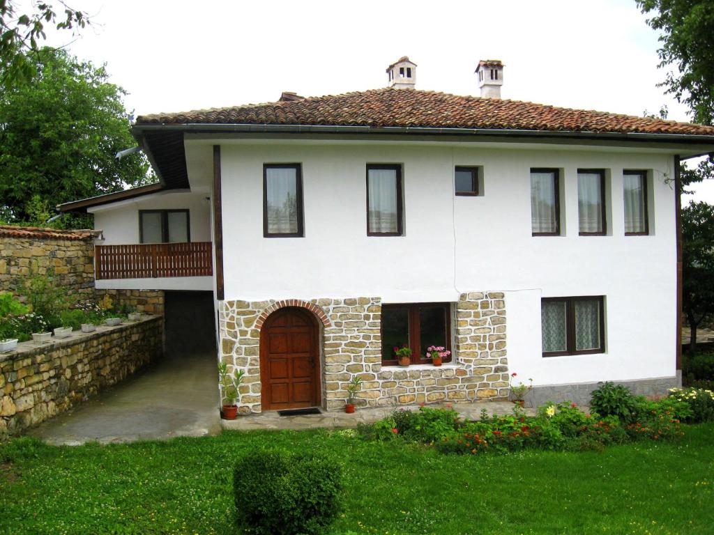 a white house with a red door and a yard at Elefterova kashta in Arbanasi