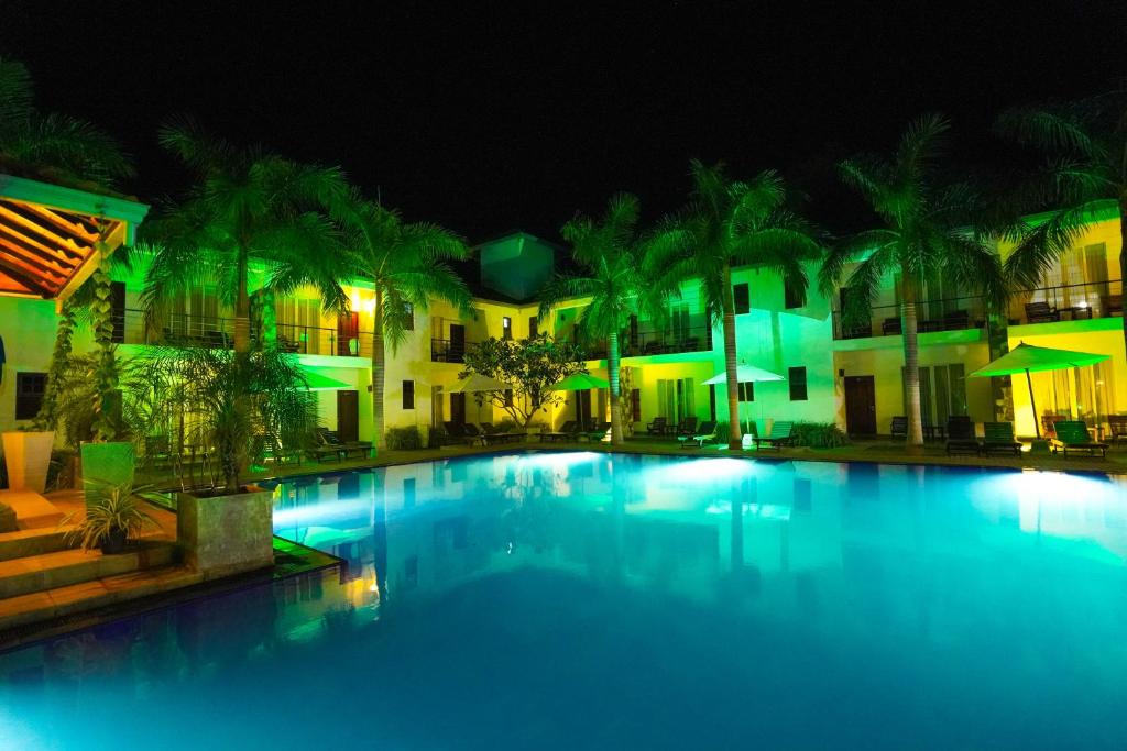 a large swimming pool in front of a hotel at night at Hotel Tamarind Tree in Tissamaharama