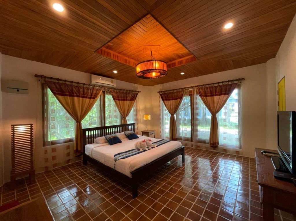 a bedroom with a large bed in a room with windows at Green Tree Resort กรีนทรี รีสอร์ต in Ban Nong Ho