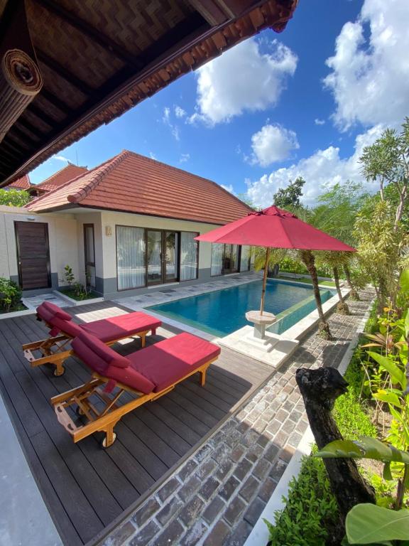 a wooden deck with a pool and a red umbrella at The Awan Villas - CHSE Certified in Seminyak
