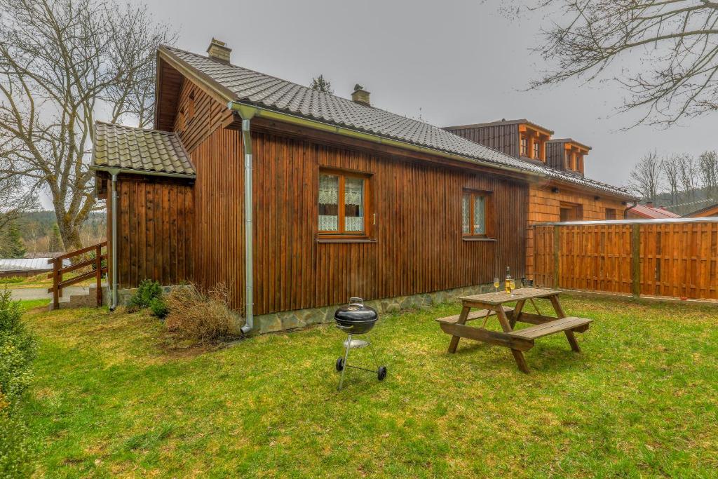 a small wooden house with a grill and a picnic table at Chalupa Prášily in Prášily