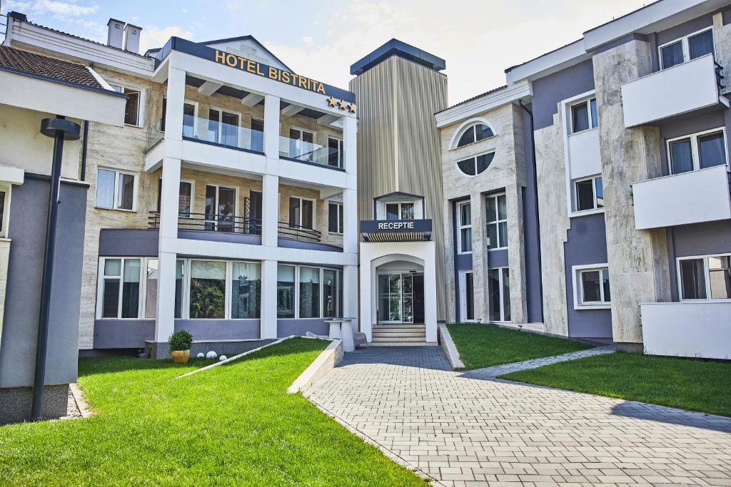 an apartment building with a driveway and grass at Hotel Bistrita in Bistriţa