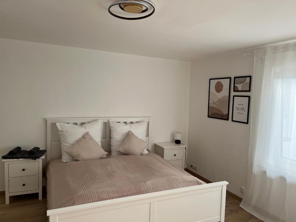 Dormitorio blanco con cama con almohadas blancas en Moderne Ferienwohnung in der Festspielstadt Bayreuth - zentral und dennoch ruhig gelegen en Bayreuth
