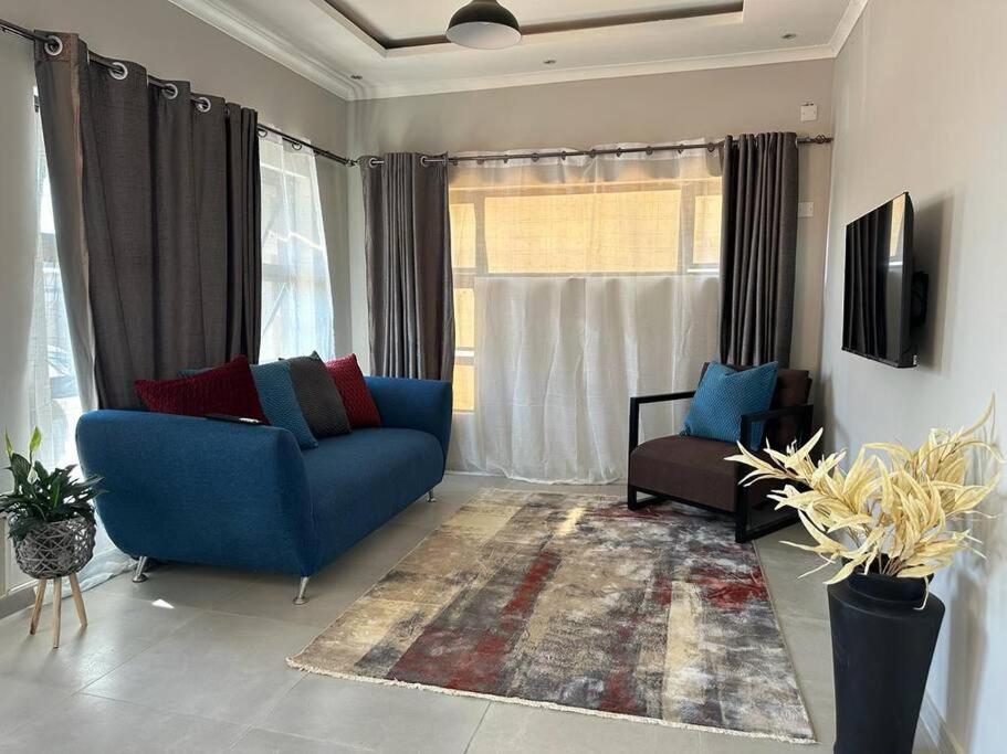 salon z niebieską kanapą i oknem w obiekcie The Urban Hub in Block 5 w mieście Gaborone