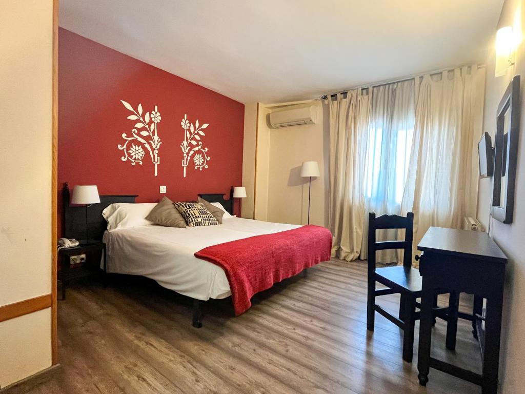 1 dormitorio con cama y pared roja en Hotel Venta Magullo en La Lastrilla
