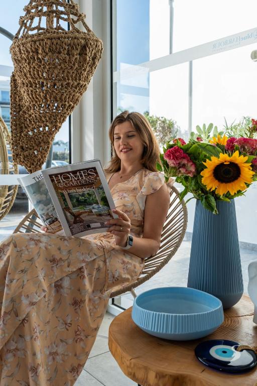 a woman sitting in a chair reading a magazine at Blue Harbour Boutique in Ayia Napa