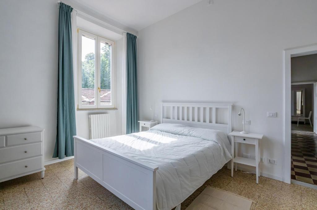 a white bedroom with a bed and a window at Lucca Historic & Cozy Central Apartment! in Lucca